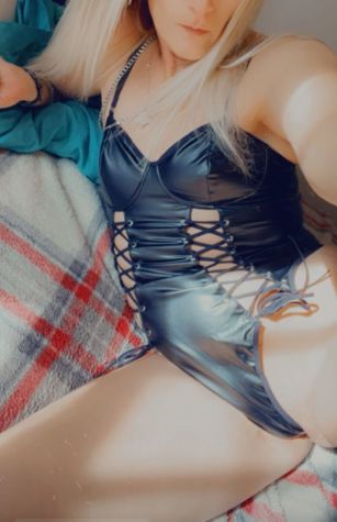 Blonde hotwife posing in sexy black lace-up lingerie for a seductive bedroom selfie