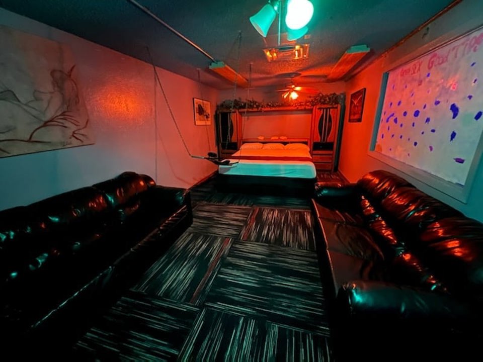 Club Encounters playroom with bed and lounge seating