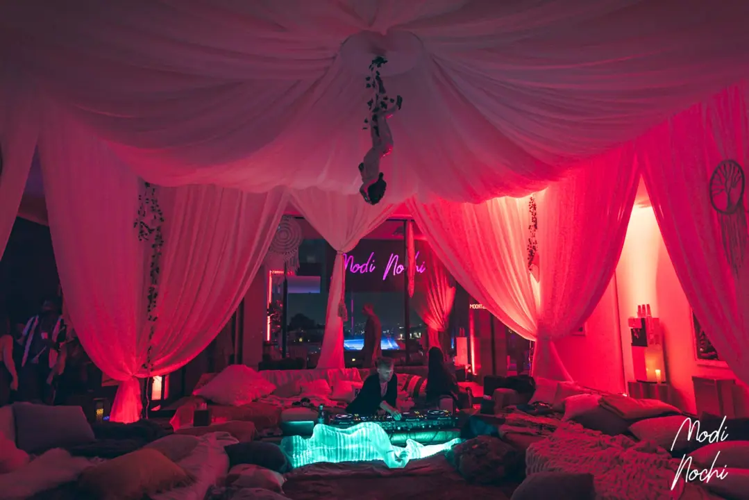 Lounge interior with red lighting, draped decor and DJ setup