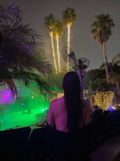 Nighttime pool area with colorful lighting and palm trees at Sea Mountain Inn Lifestyles Nude Spa Resort in Desert Hot Springs, California