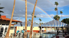Exotic Dreams Resort Hotel pool courtyard with striped cabanas and a rainbow in Palm Springs, California
