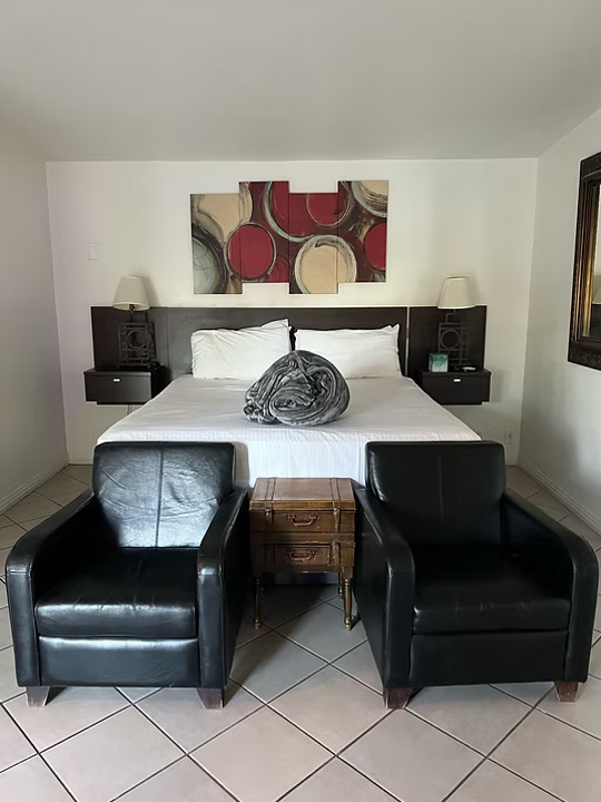 Boutique guest room with bed and black leather chairs