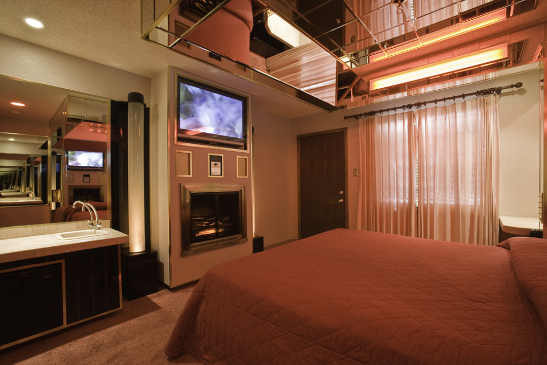 Standard suite bedroom with fireplace, mirrors and red lighting
