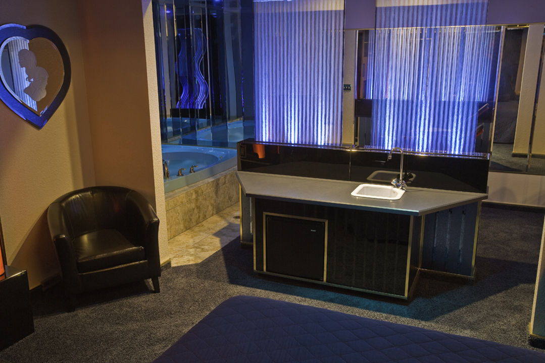Deluxe suite wet bar beside a blue-lit whirlpool