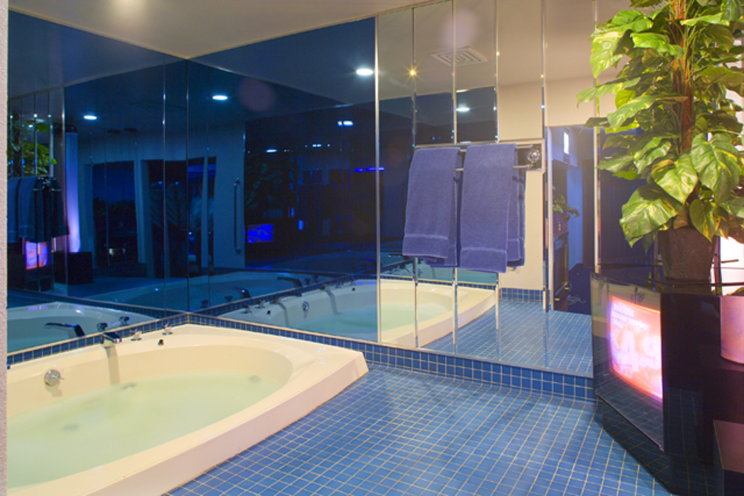 Private suite whirlpool surrounded by mirrored walls and blue tile