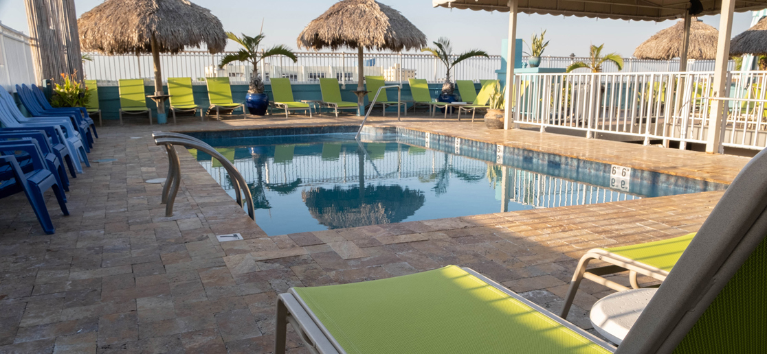 Rooftop pool with lounge chairs and tiki umbrellas