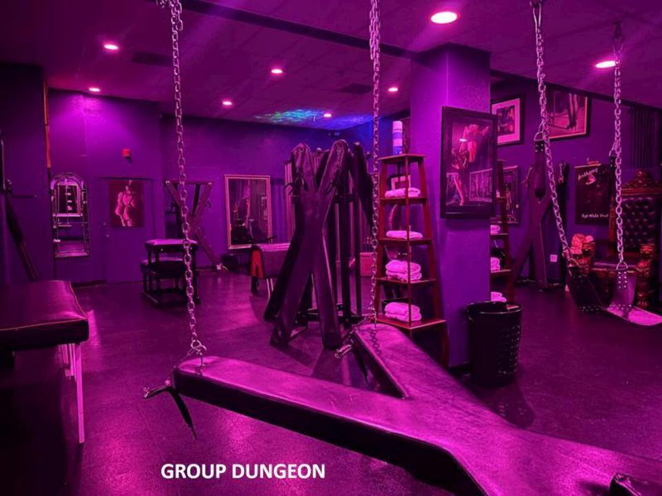 Group dungeon with purple lighting and BDSM play equipment