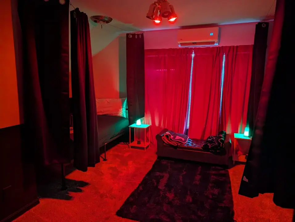 Red-lit private play room with curtained beds