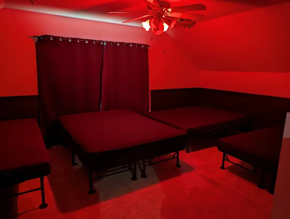 Red-lit group play room with padded platforms