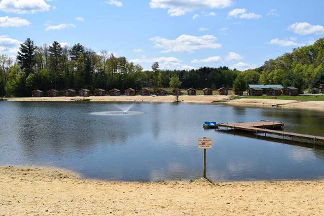 Pond and sandy beach with dock and cabins