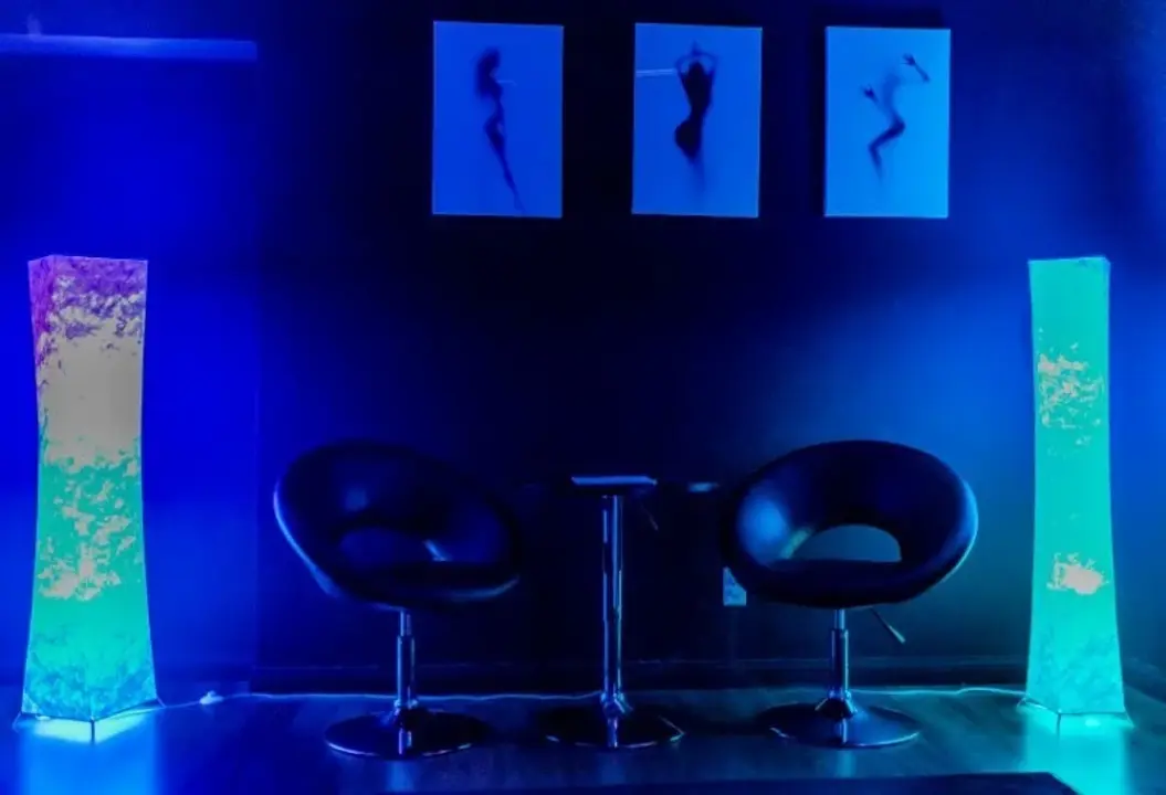 Blue-lit lounge seating area with chairs and wall art