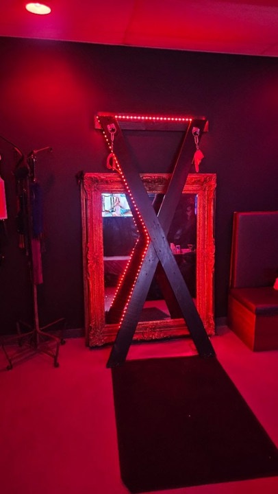 Red-lit St Andrews cross in the BDSM playroom