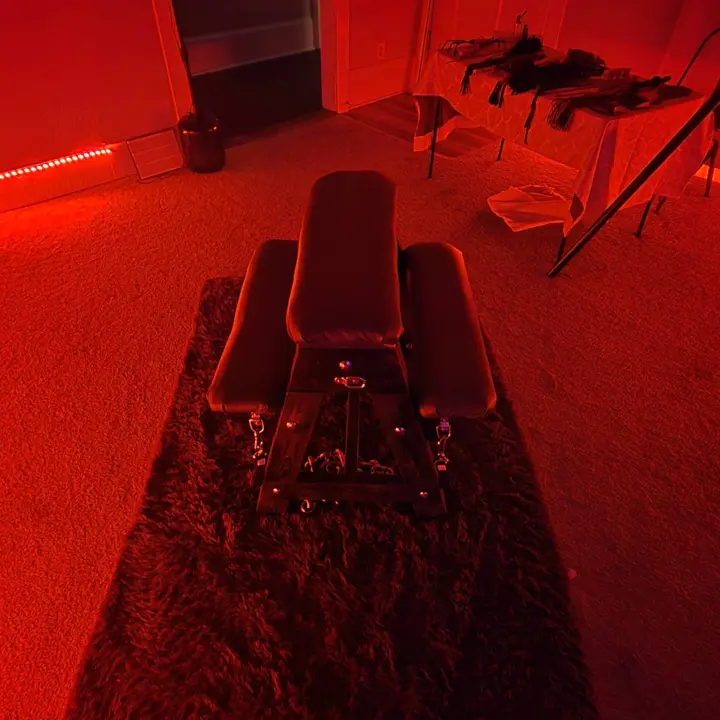 Lounge BDSM bondage bench in the red-lit playroom