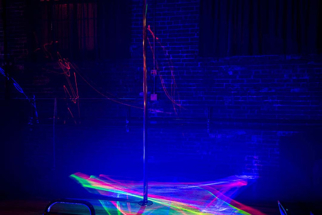 Dance pole under blue and laser lighting
