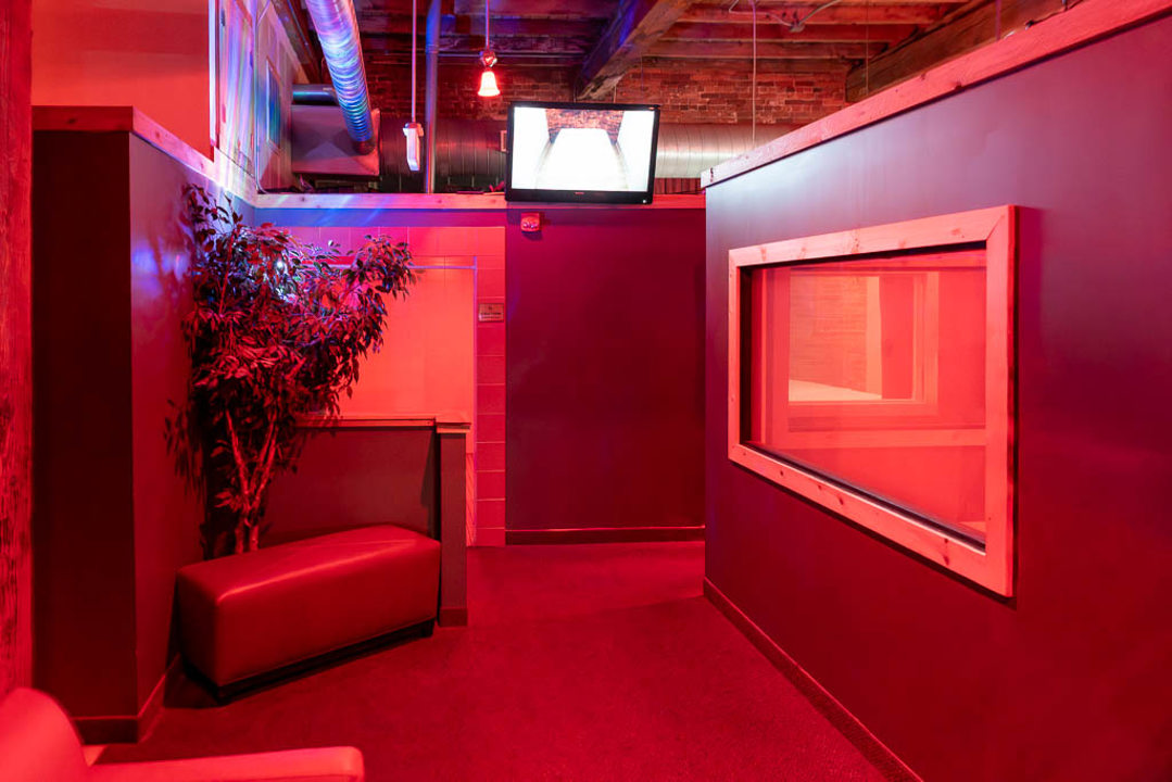 Red-lit interior corridor with seating and viewing window