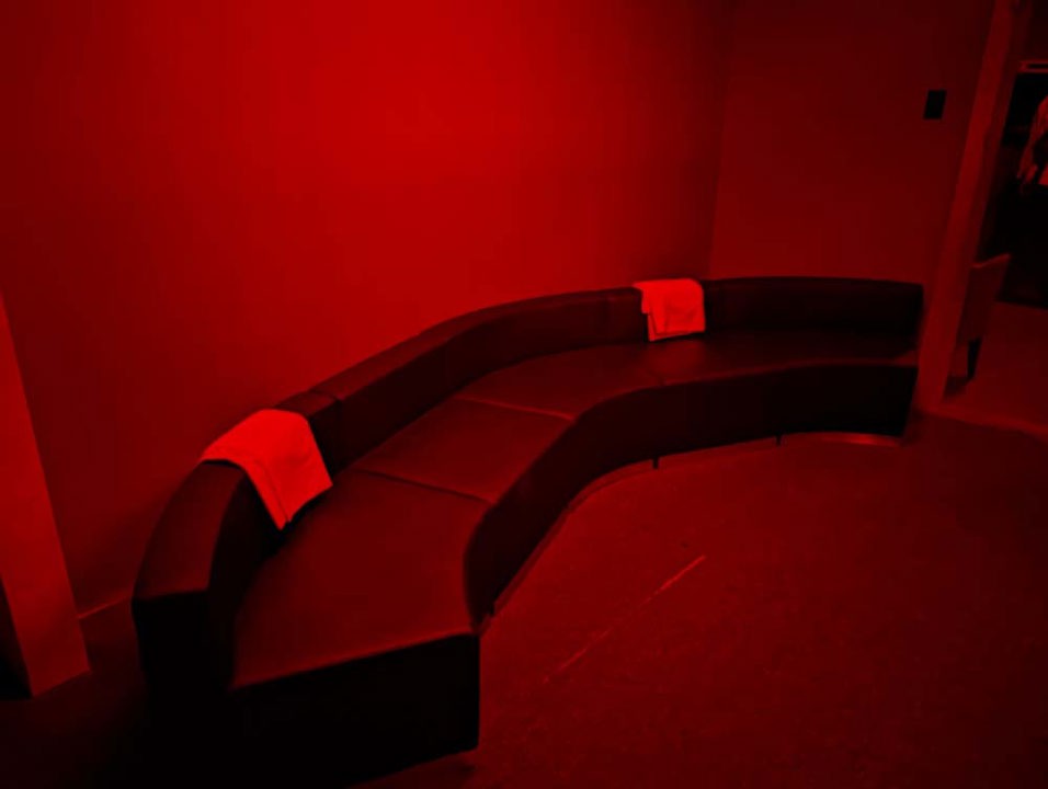 Curved lounge seating in a red-lit private social area