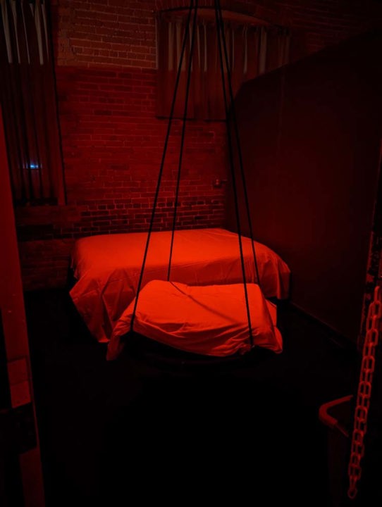 Red-lit themed room with suspended swing and padded platform