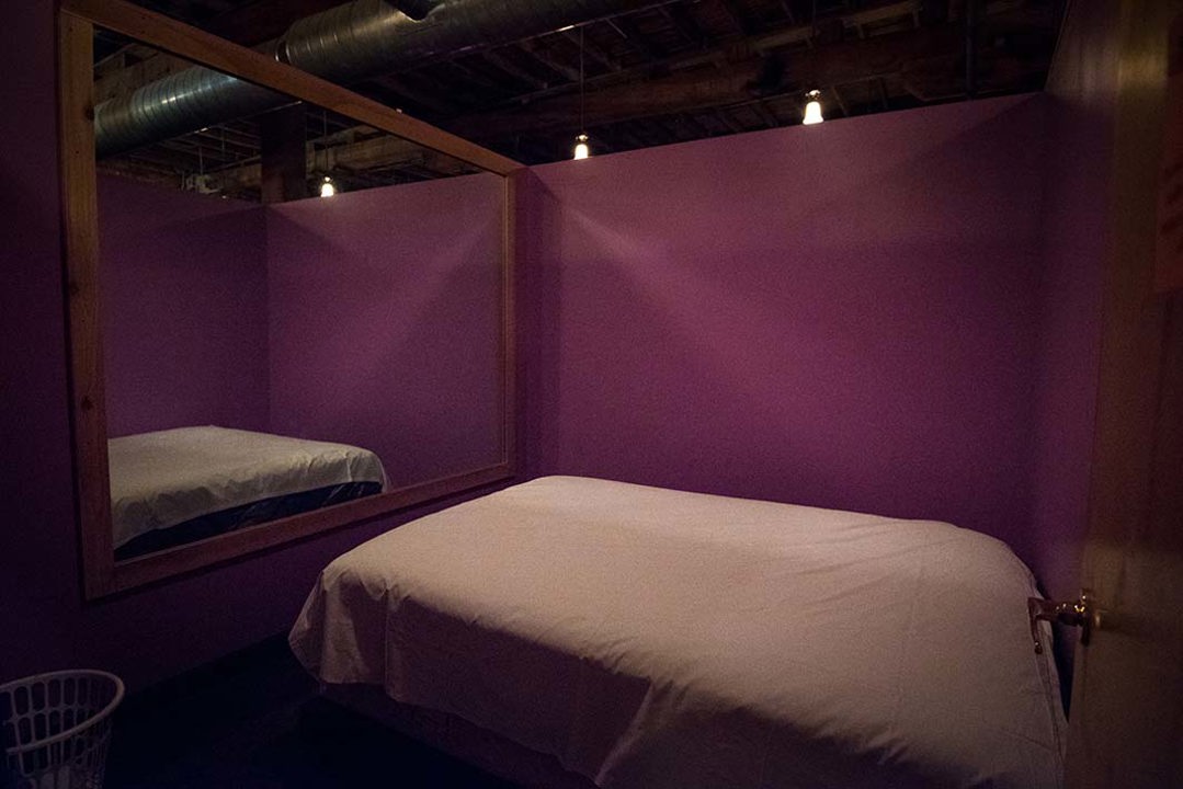 Purple private room with padded bed and wall mirror